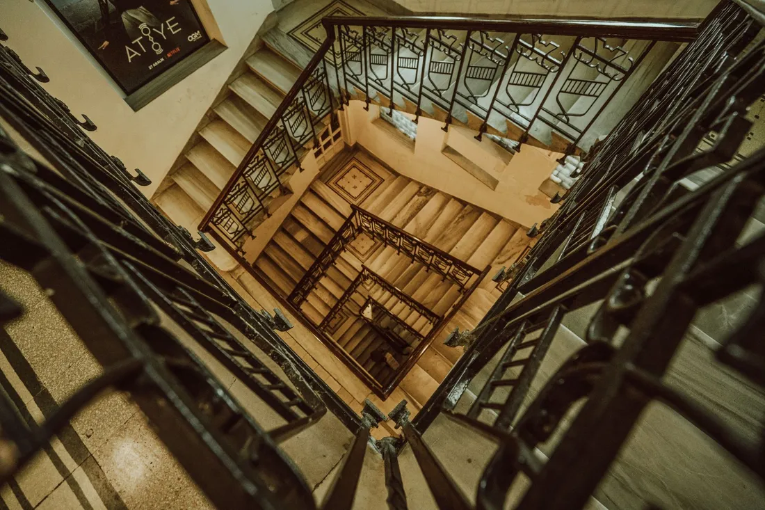 Enges Altbau-Treppenhaus mit Geländer und hohen Decken